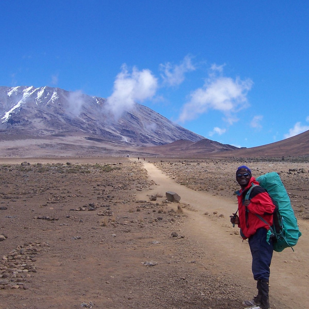 Baraka Dalali, founder and licensed Kilimanjaro guide, on the trail with Kilimanjaro behind him